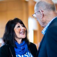 President Philomena V. Mantella is shaking Robert Thompson's hand. Ellen Thompson is in the background.